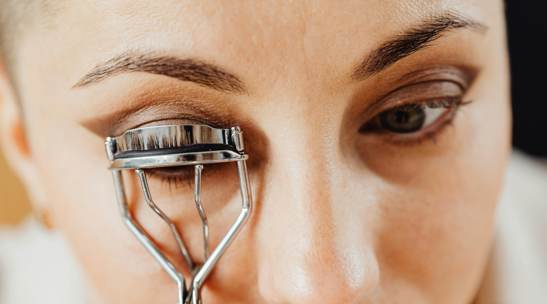 Woman curling her eye lashes 